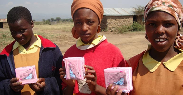 three teenagers holding sanitary kits