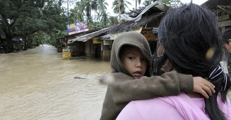 a mother carrying her son after a flood