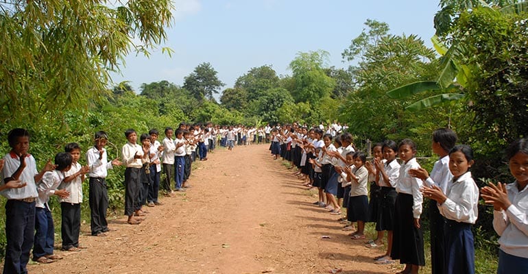 school children lined up on the sides of a road