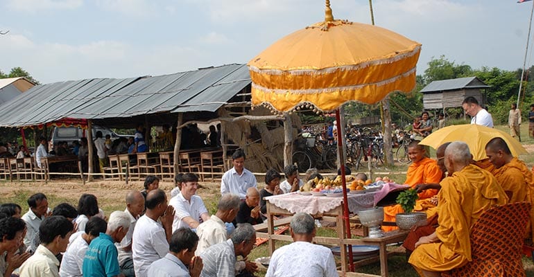 a group of people sitting in front of a group of monks