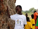 a young boy standing next to a tree