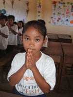 a young girl with her two hands in a praying position